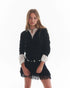 Chaleco LILO negro de cashmere combinado con blusa blanca y falda con flecos, modelo posando con look moderno.
