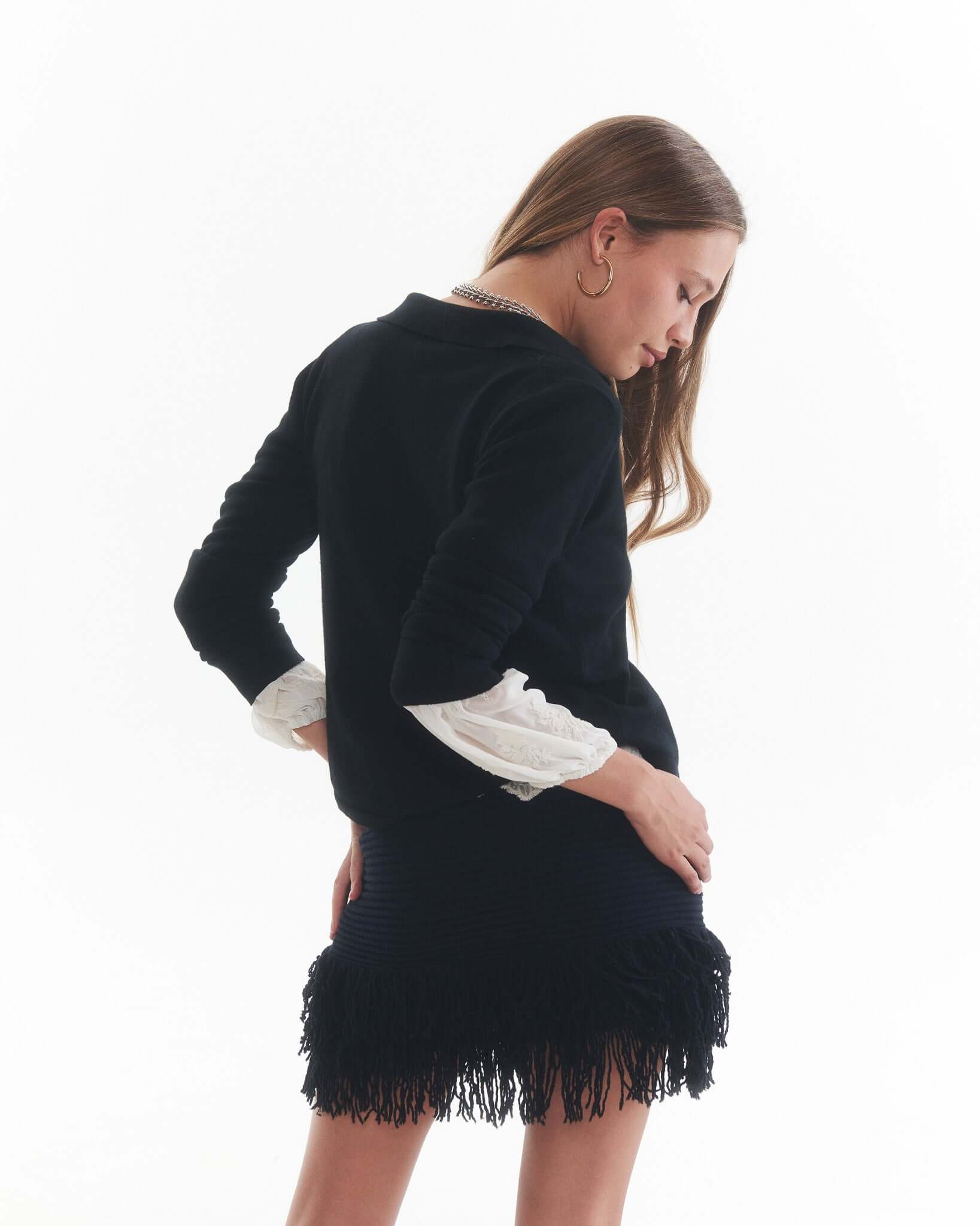 Mujer usando chaleco LILO negro, parte de la colección Essentials, con falda de flecos, mostrando comodidad y estilo.